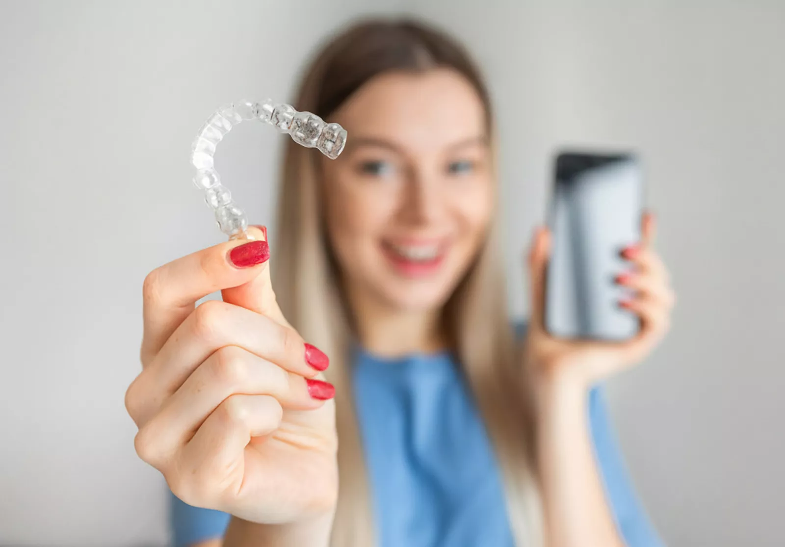 Ragazza con in mano apparecchio invisibile e smartphone